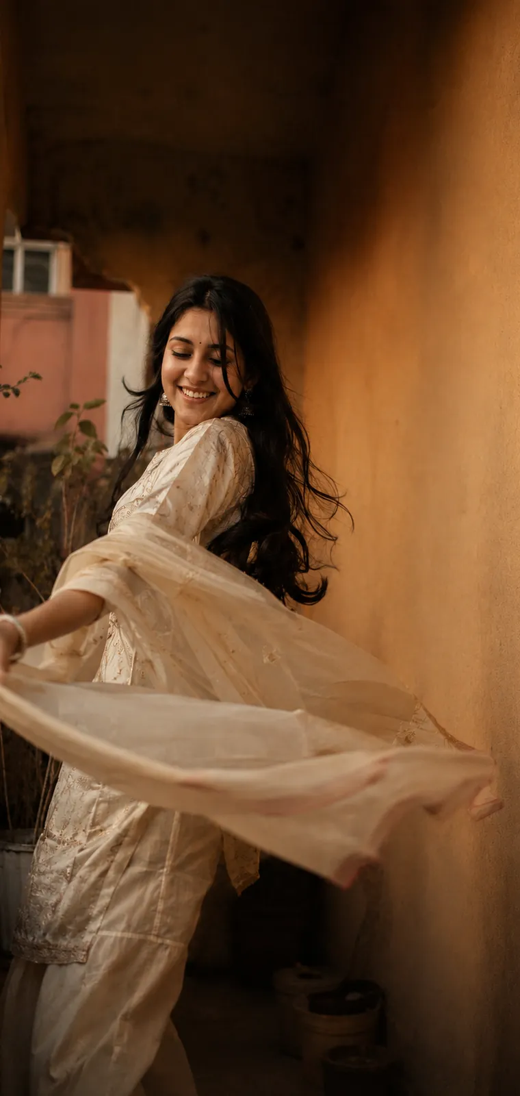 A young woman turning mid-dance in a sunlit corridor, her dupatta sweeping out